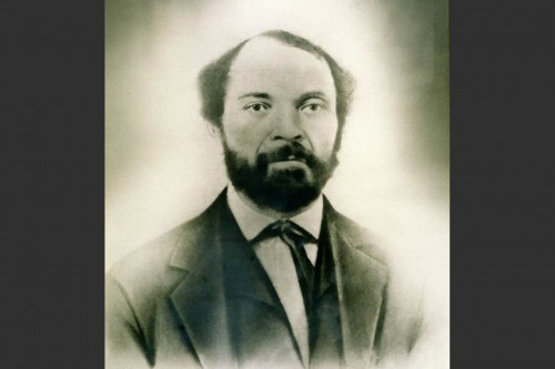Photo of Robert Hughes as a middle-aged man, bearded and wearing a jacket and tie
