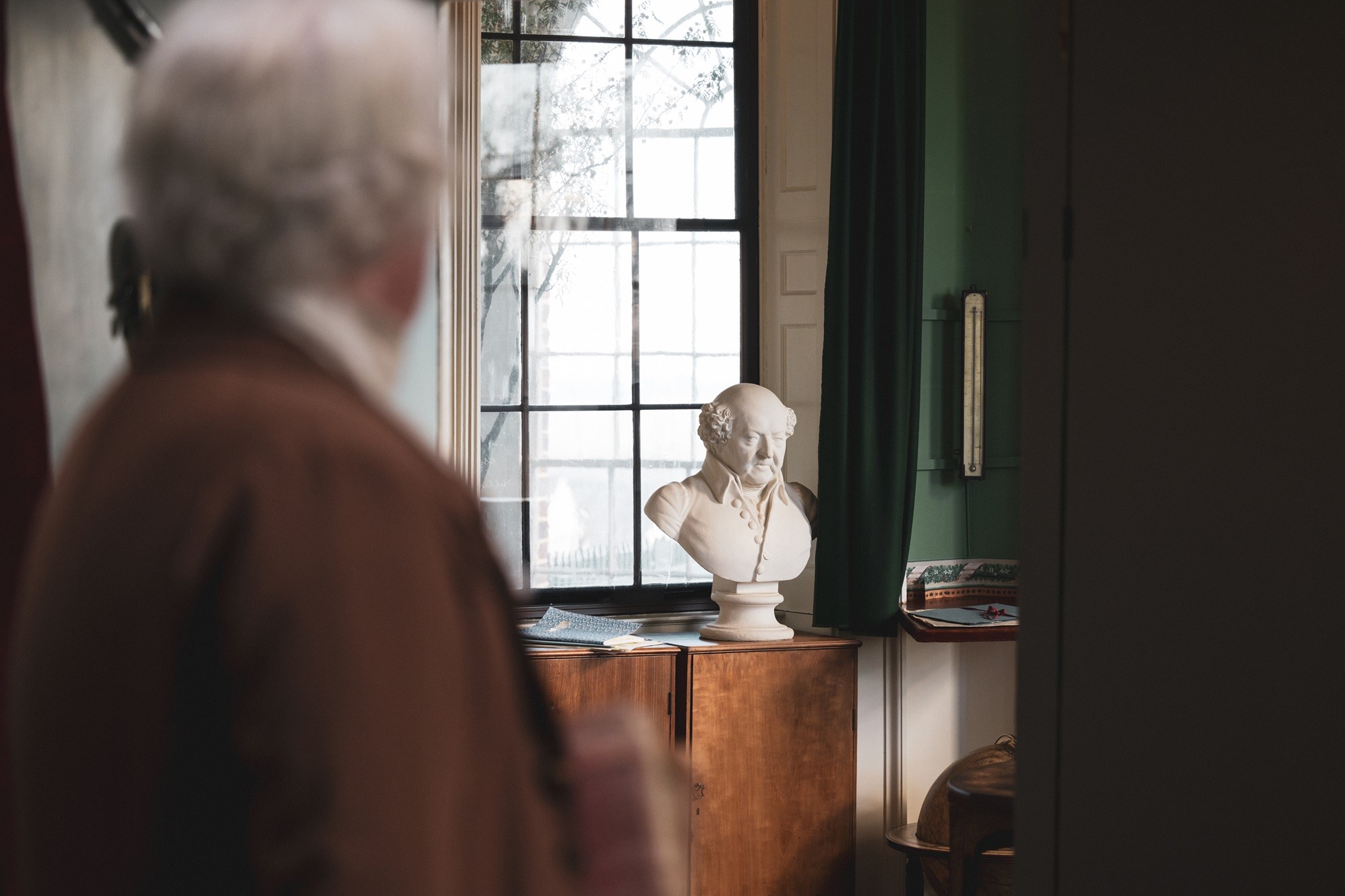 Bill Barker, as Thomas Jefferson, looks at the bust of John Adams on display in Monticello's Cabinet