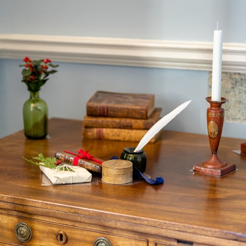 Antique desk and chair with a Christmas gift, quill, holly, candle, and books on top