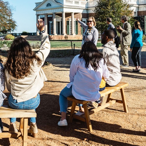 Photo of people on benches by Monticello's West Lawn. Outdoor tours and activity centers are available seasonally on the mountaintop.