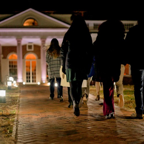 A group of people walking along a warmly lit path to take a holiday tour of Monticello, located near Charlottesville, VA in Albemarle County