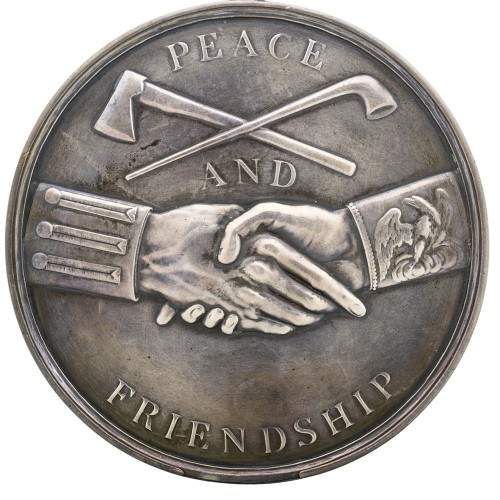 The reverse of a peace medal depicting a handshake