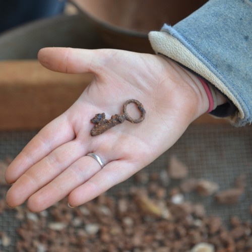 An archaeologist holds part of an iron skeleton key recovered during excavations