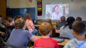 Students sit at desks in a classroom while viewing a virtual tour of Monticello on a large projection screen.